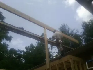 Carpenter setting a ridge beam over a new addition frame — Ice Dam Removal by Roofing Brothers in Buckhead