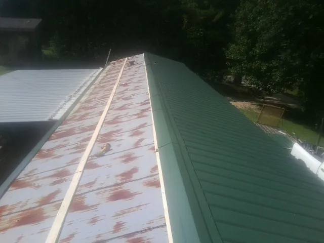 Old rusted panels beside newly installed green metal roofing — Wind Damage Roof Repair by Roofing Brothers in Buckhead