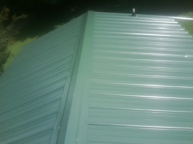 New green metal panels meeting at the ridge of a roof — Flat Roof Repair work by our crew in Buckhead