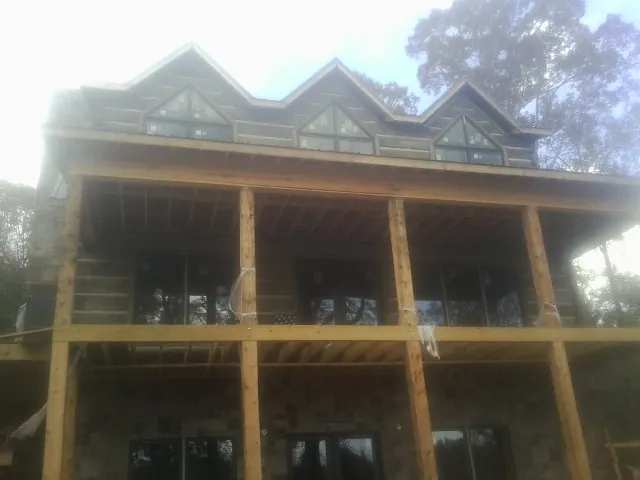 Dormers and porch framing on a large log home under construction — Roof Coating work by our crew in Buckhead