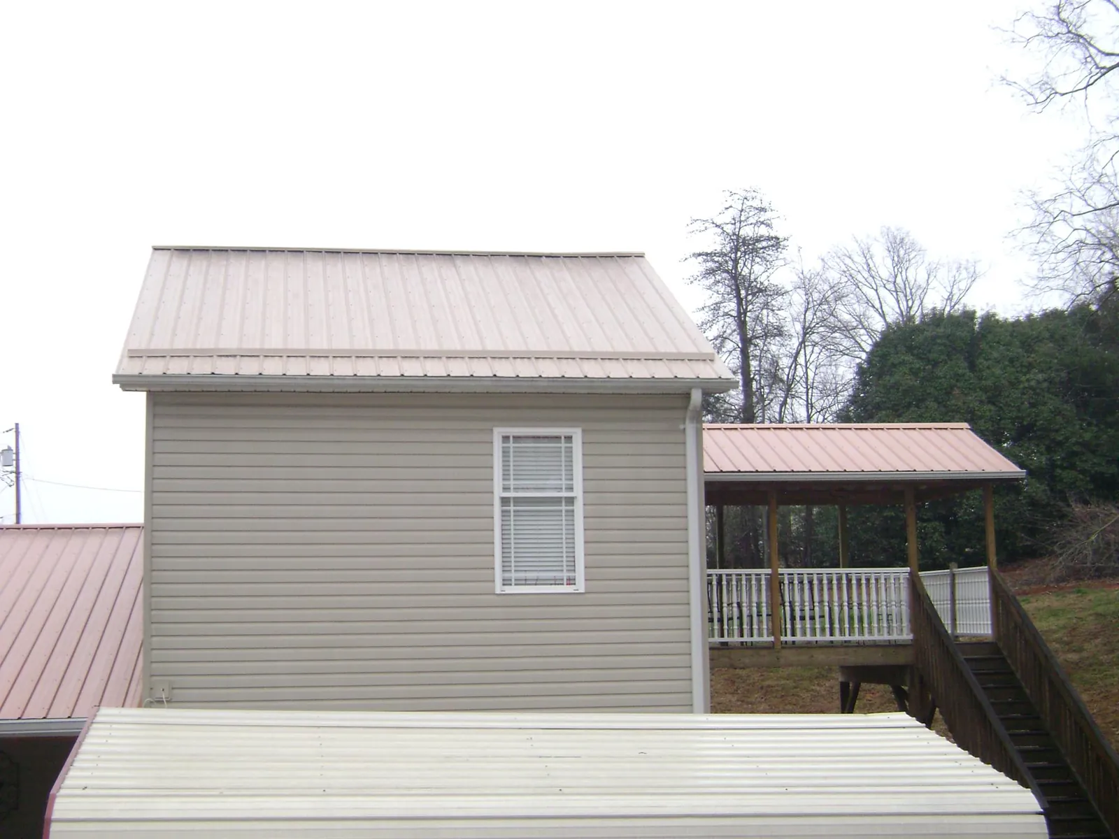 Tan metal roofs on a two story addition and attached porch, from a Roof Replacement job in Buckhead