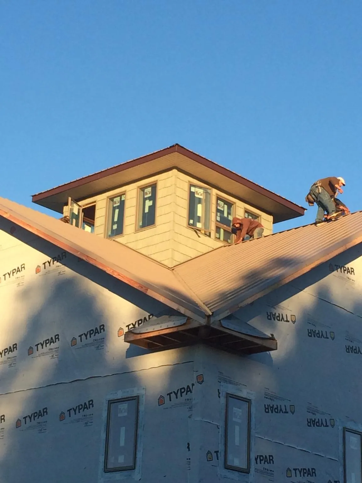 Roofers working around a rooftop cupola on a new metal roof at sunset — Roof Waterproofing in Buckhead by Roofing Brothers